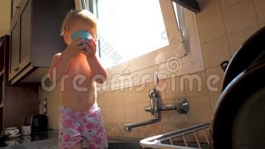 喘息，呛人的概念.. 儿科背景。 幼儿一边喝水一边站在厨房的水槽里.. 宝贝女儿